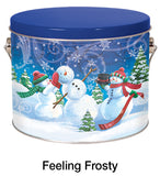 A round metal tin with a blue lid and a winter scene printed on the front, showing three snowmen in a snowy landscape. The text 'Feeling Frosty' appears below the tin on a white background.
